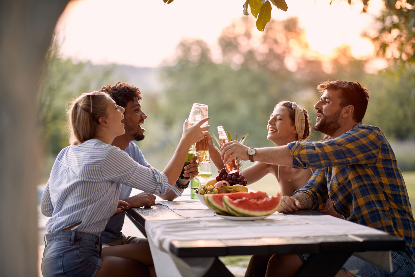 Group of young adults having drinks at picnic table