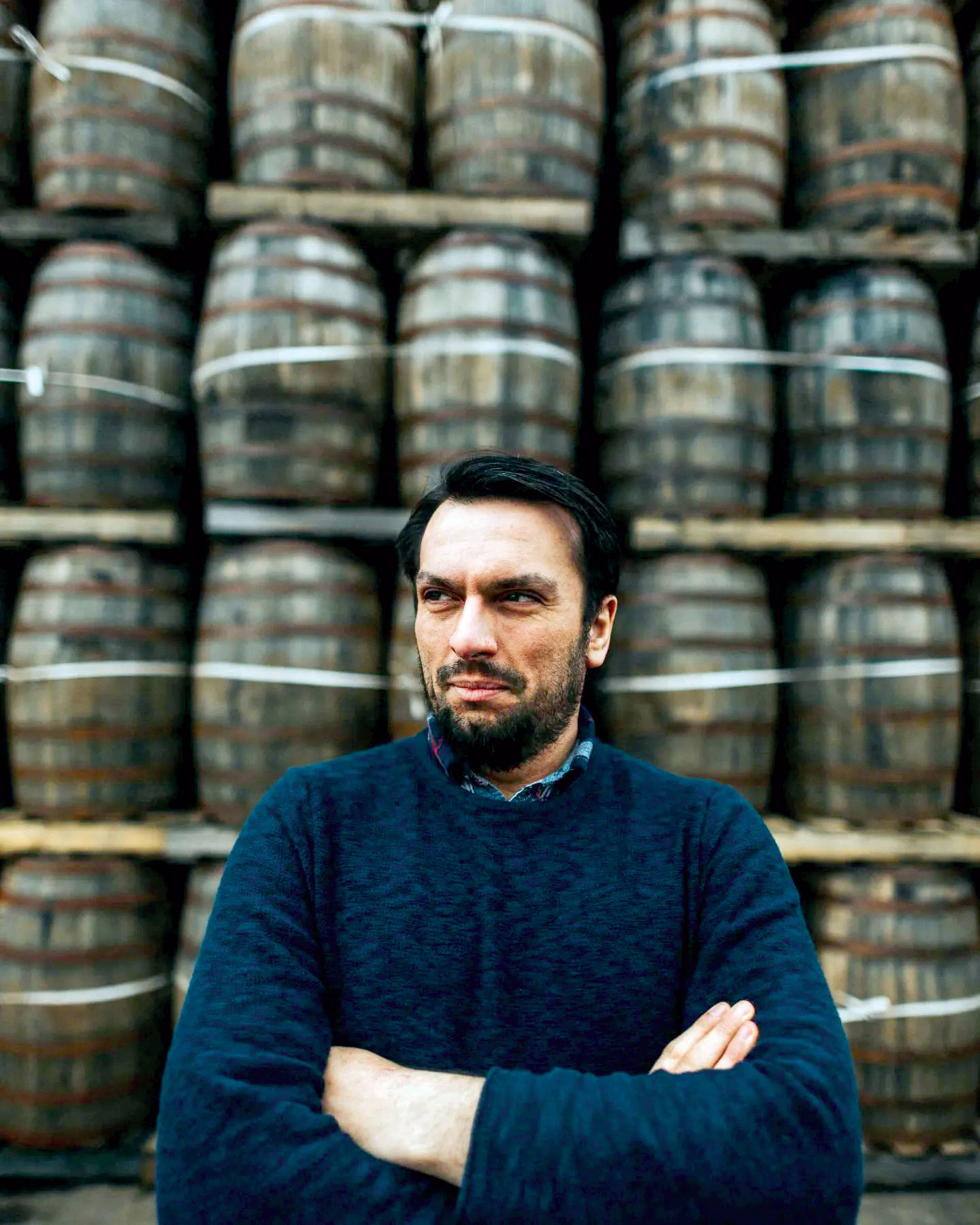 Bry Simpson, arms folded, with stacks of barrels in background