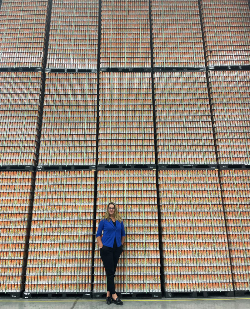 Maddy standing in front of wall of cans