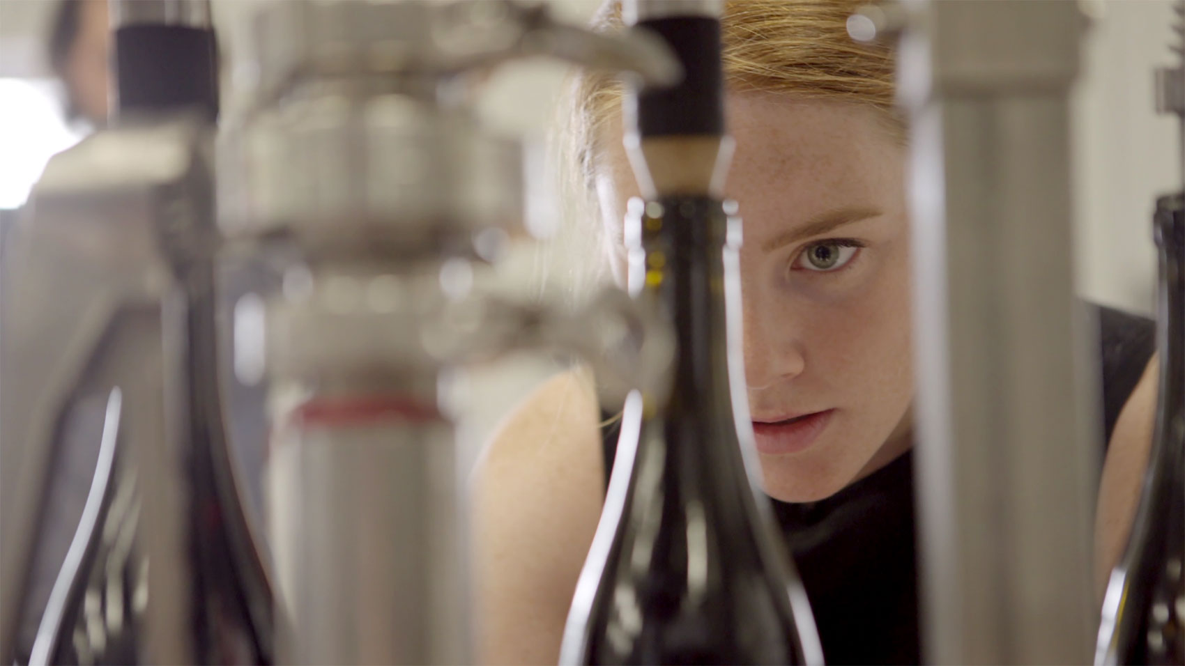 A winemaker looking through a glass bottle