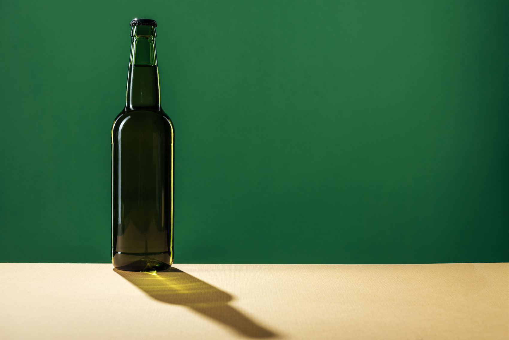 Silhouette of beer bottle casting shadow along table