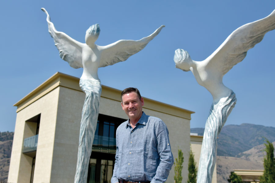 Mark Beringer standing, smiling in front of art installation