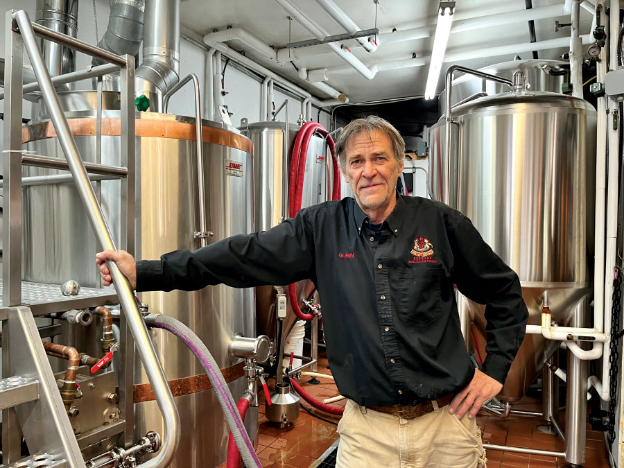 Glenn Kervin leaning against brewing equipment