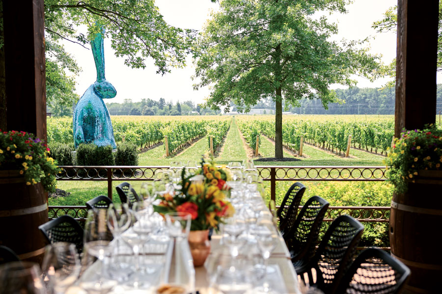 Photo of from inside veranda of table setting, vineyard, and big, blue inflatable bunny in the background