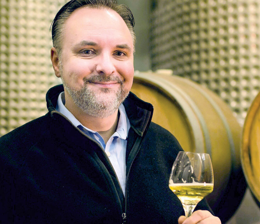 Dominic Rivard smiling for photo with glass of cider in hand