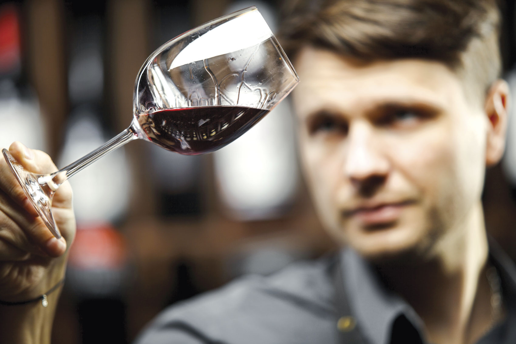 Man inspecting glass of wine held up at an angle