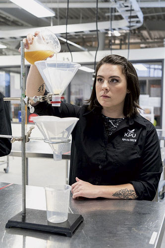 Student in lab carefully pouring beer into beaker