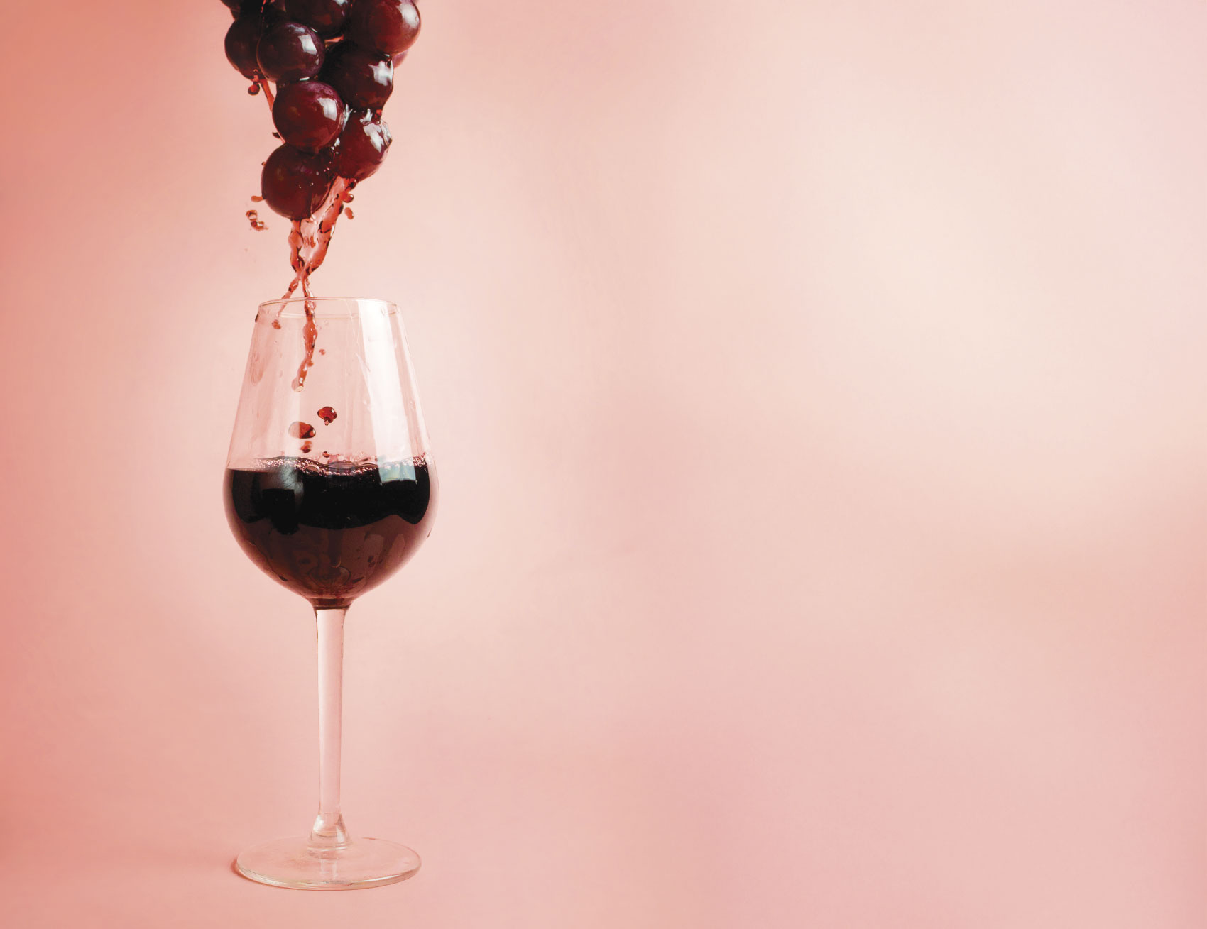 Wine being poured over grapes into a wine glass