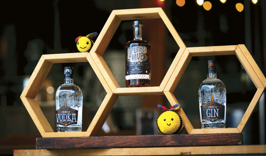 Three bottles of honey infused liquor on hive-shaped shelving