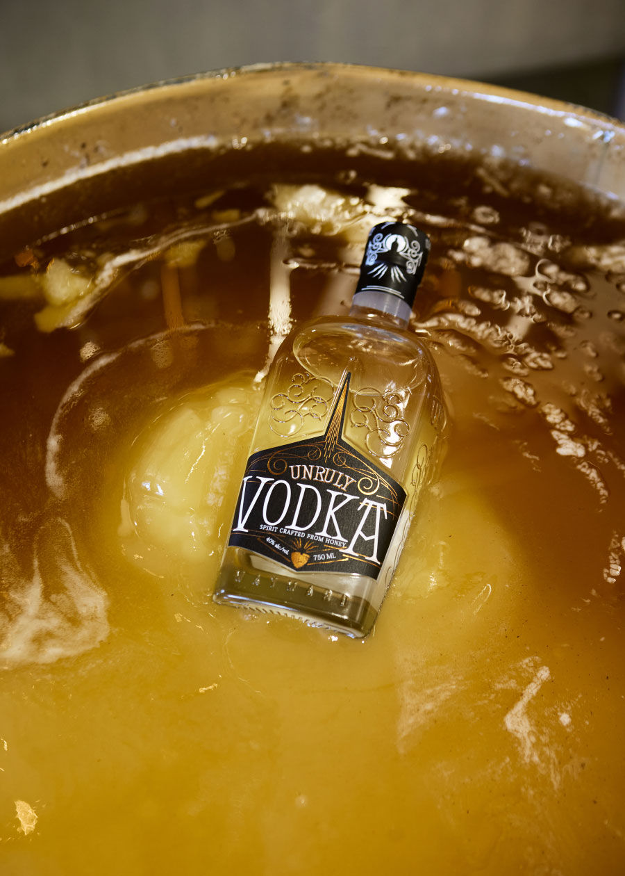 bottle of vodka sitting in a shallow vat of honey