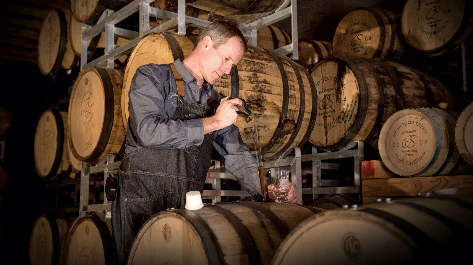 Tyler Dyck pouring a whisky sample from a barrel