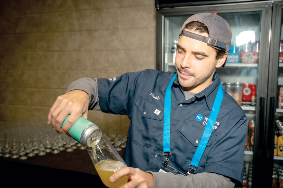 Vendor pouring a can of beer into a glass
