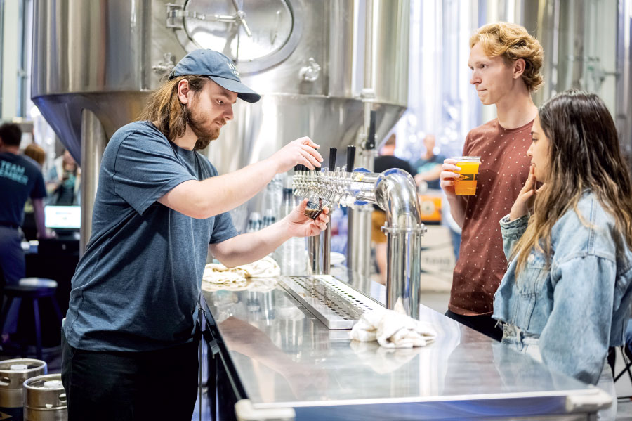 Man pouring draft beer for two customers