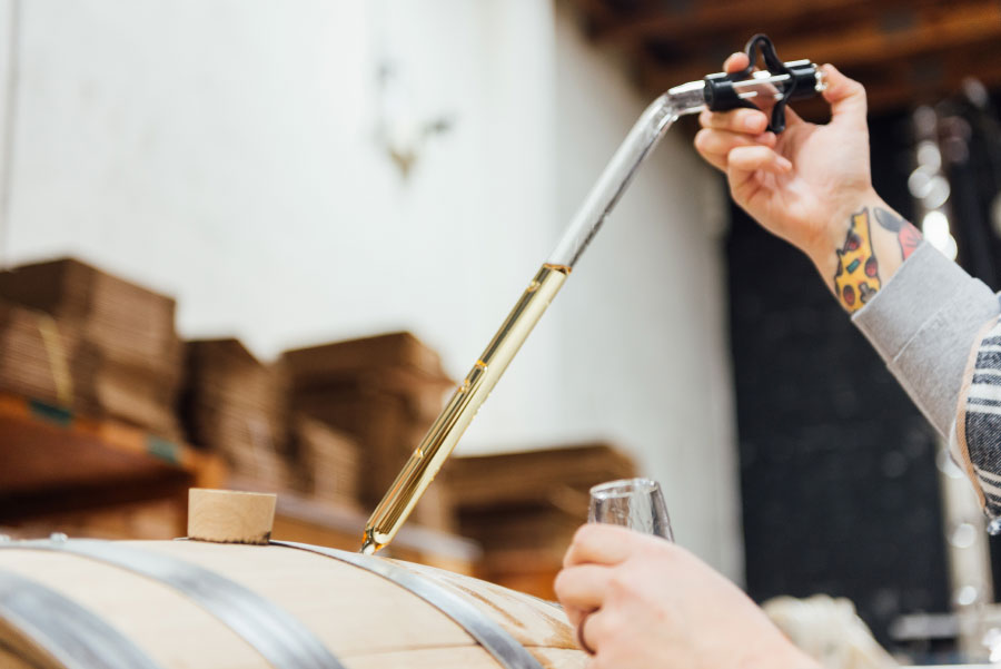 Carefully extracting whisky from barrel for tasting