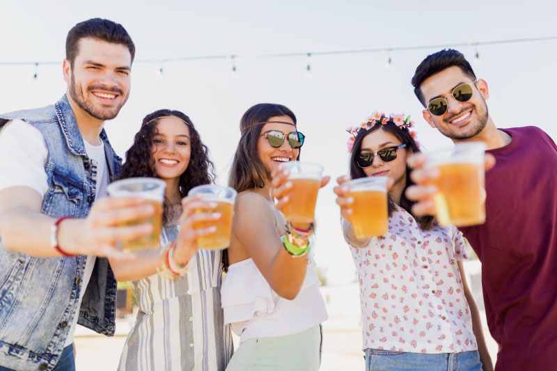 Group of smiling young adults holding glasses of beer glasses
