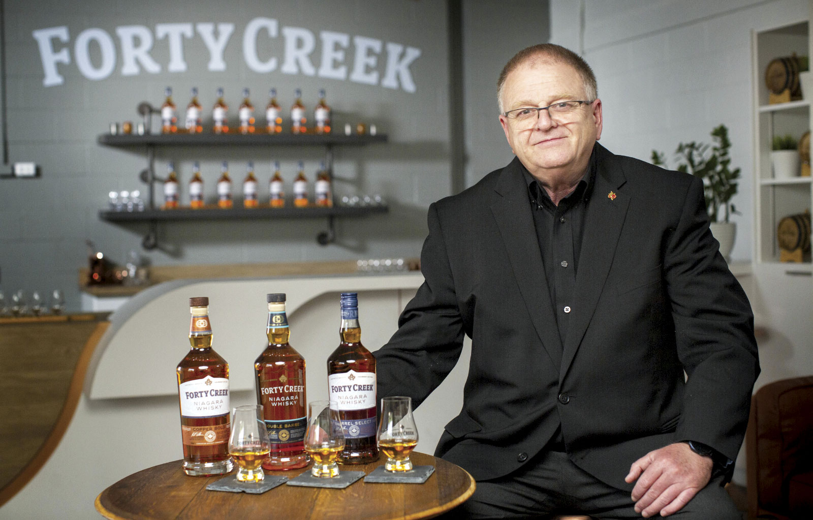Bill Ashburn sitting at table with various bottles of whisky