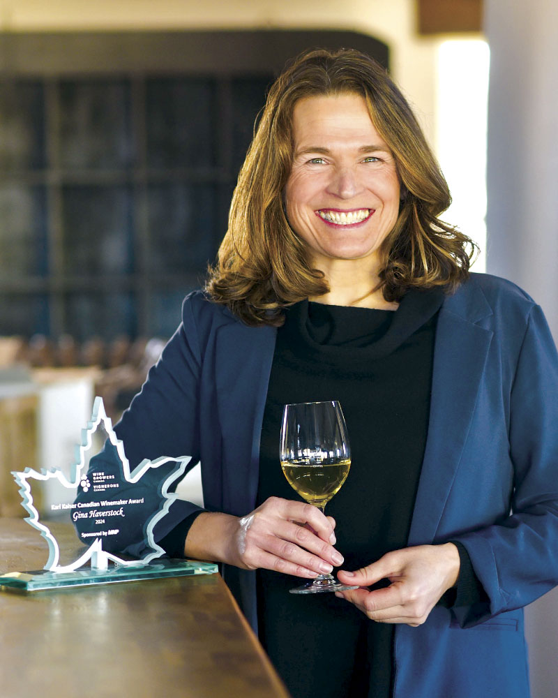 Gina Haverstock with award and glass of white wine in hand