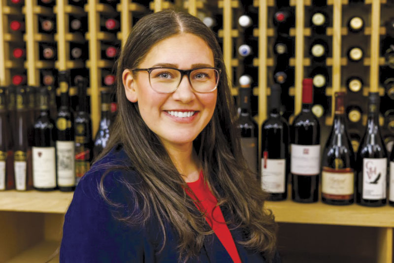 Jennifer Kelly posing for photo in front of wine rack