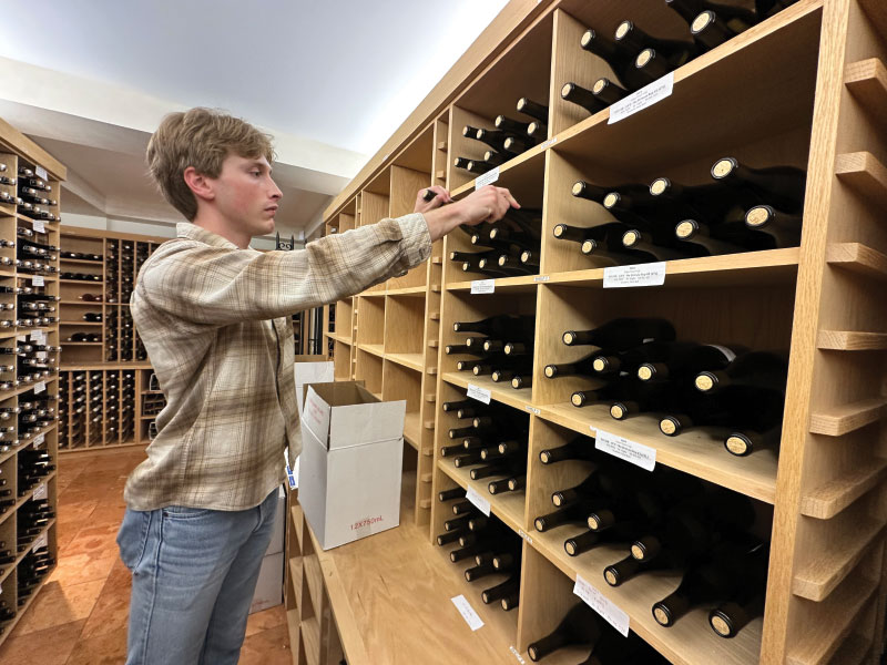 Student stocking wine on display shelves