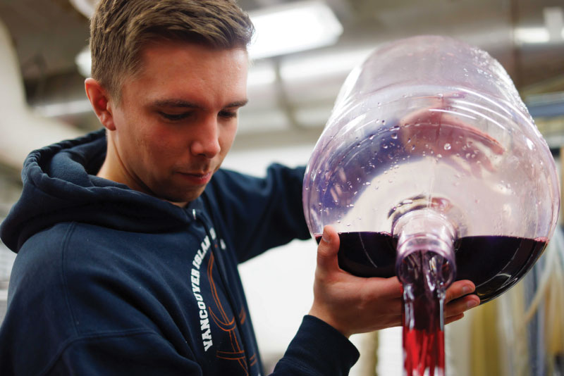 Student pouring wine into bottle