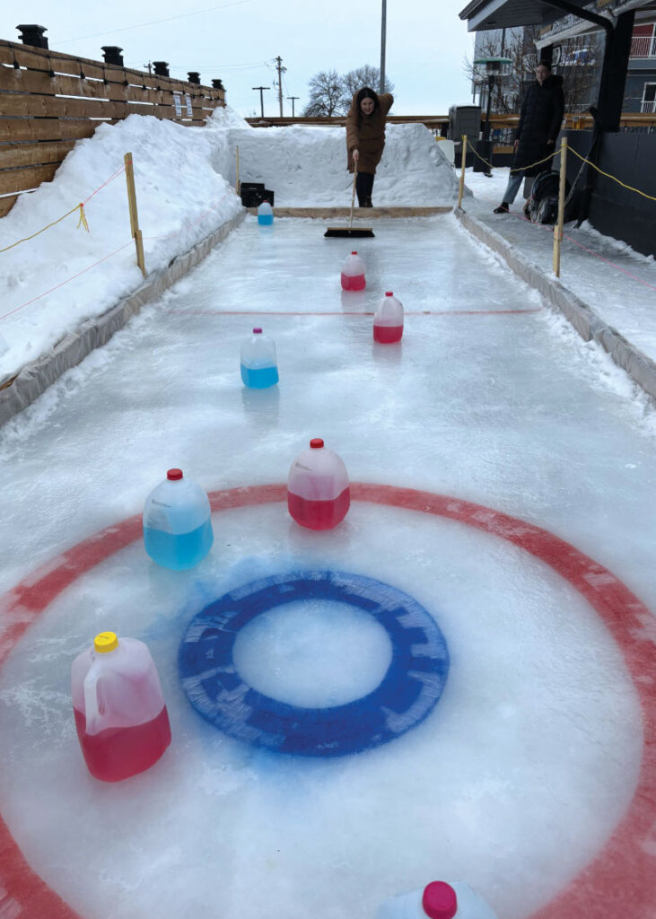 Ally Giardino pushing a milk jug down at the ice at Interlake Brewing’s rooftop patio
