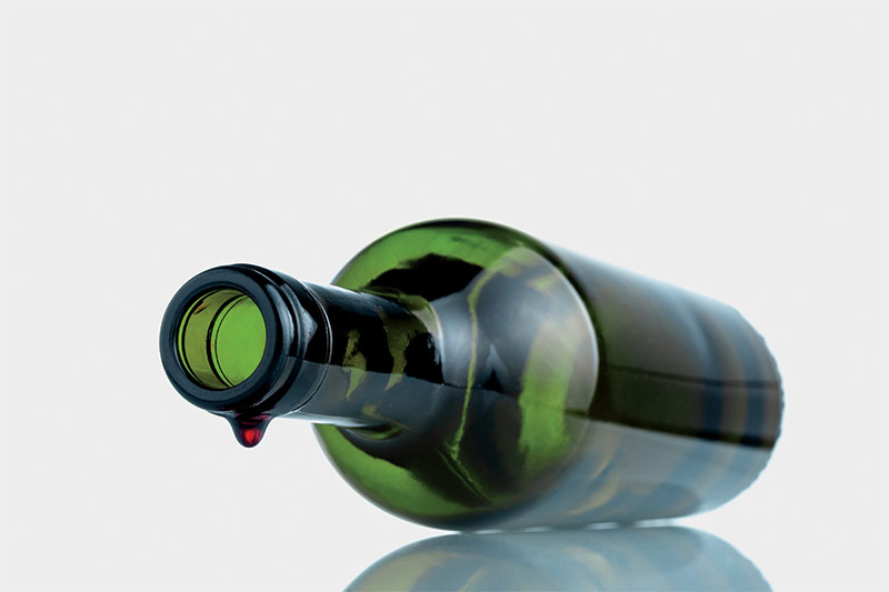 Drop of wine hanging off lip of empty wine bottle