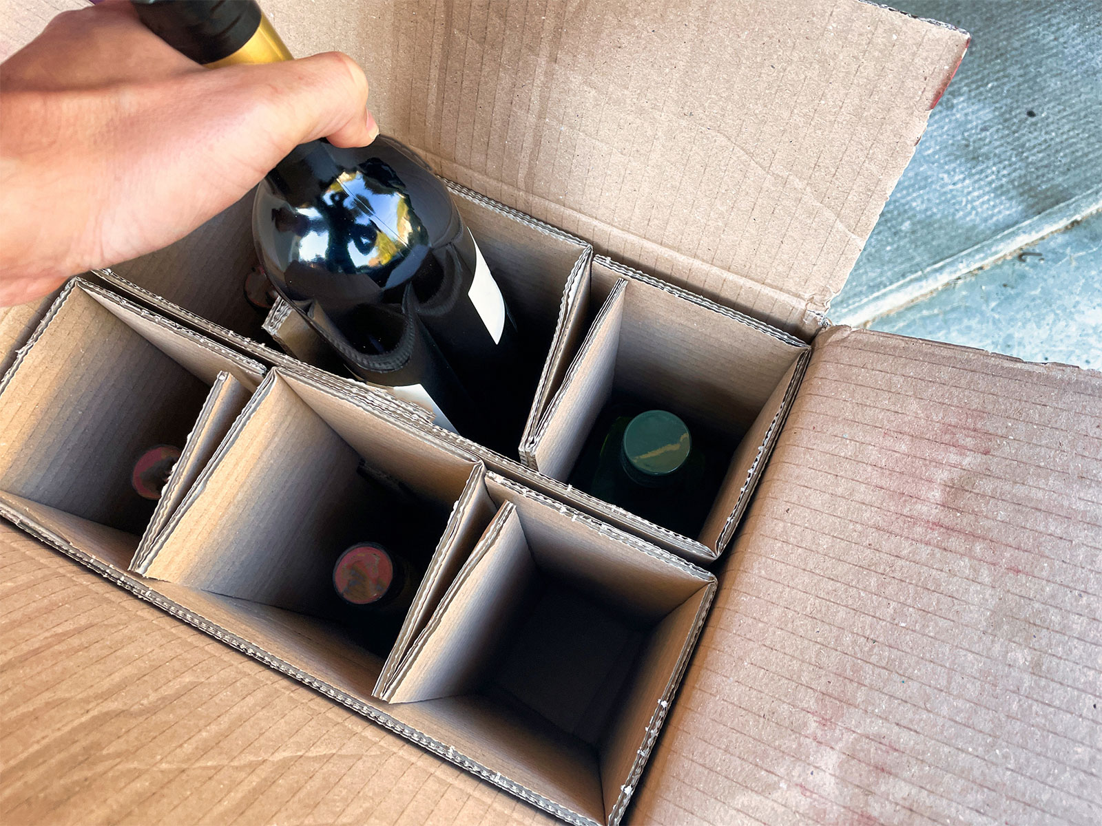 hand taking a bottle of wine out of a box
