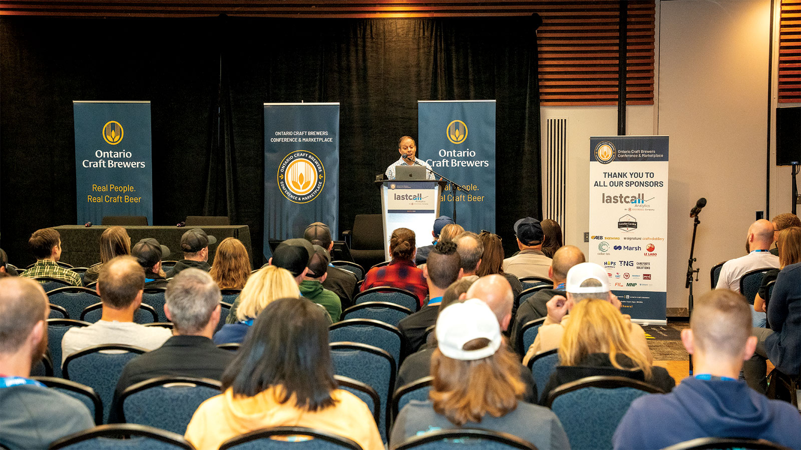Speaker at podium in front of seated audience