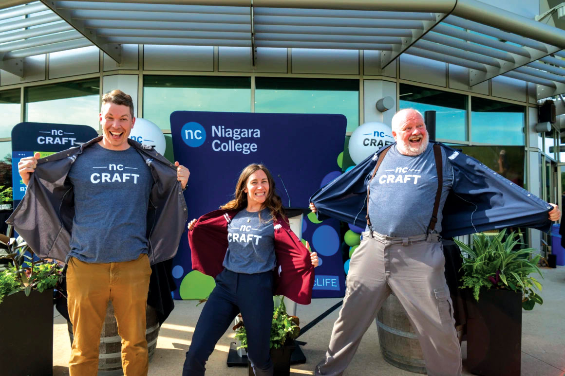 Three smiling people opening their jackets to reveal tshirts with new branding