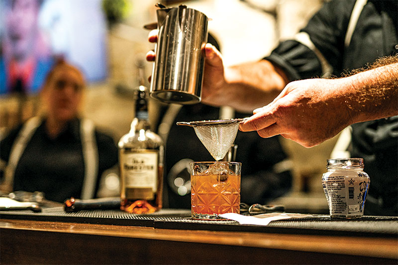 Bartender straining a cocktail into a glass