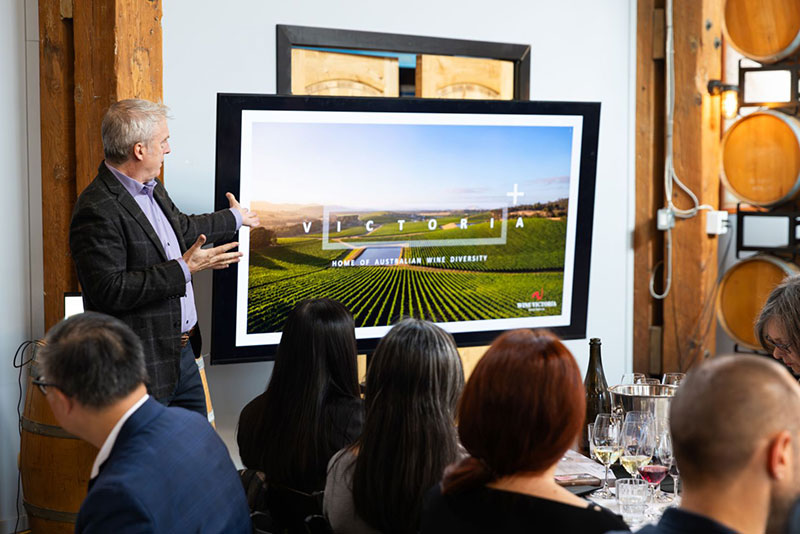 Speaker displaying photo to people seated at tables